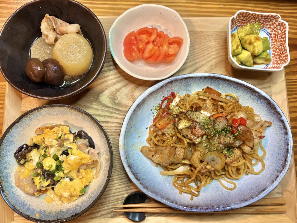 彩り豊かな夕食の献立全体写真。豚肉とキクラゲの中華炒め、焼きそば、大根の煮物などが食卓に並んでいる様子