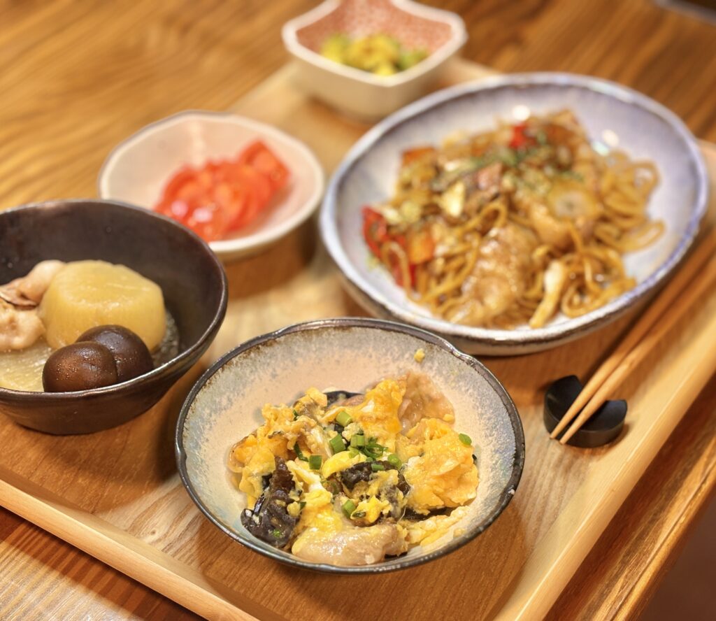 焼きそばや煮物、中華炒めなどがバランスよく配置された、夕食の献立を真上から撮影した写真