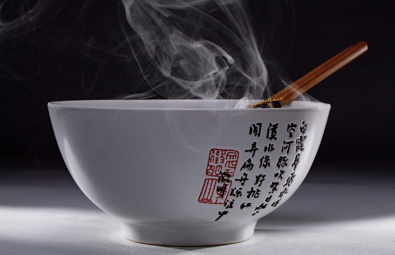 漢字の書と印章が描かれた白い丼から湯気が立ち昇ってる