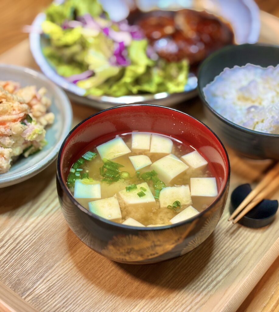 角切りの豆腐と刻みねぎが入った豆腐の味噌汁。やさしい色合いの味噌と具材が見える温かみのある一杯。