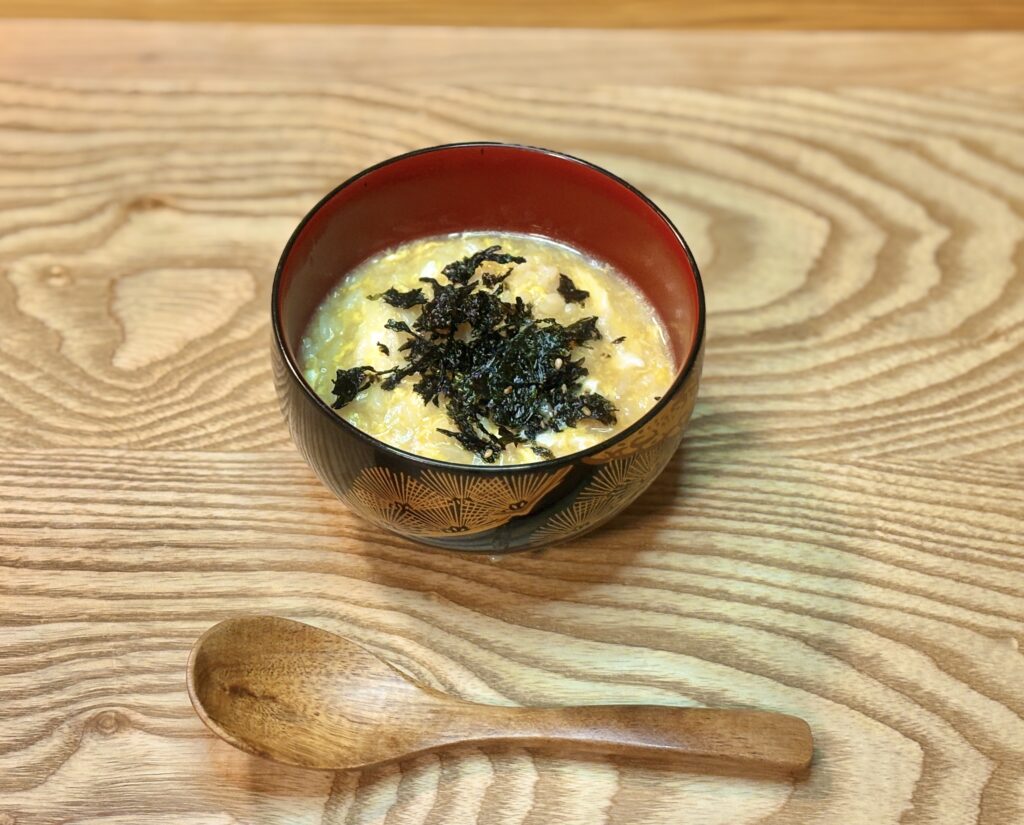 海苔をのせた卵雑炊が入ったお椀、木のテーブルに置かれたやさしい締め料理