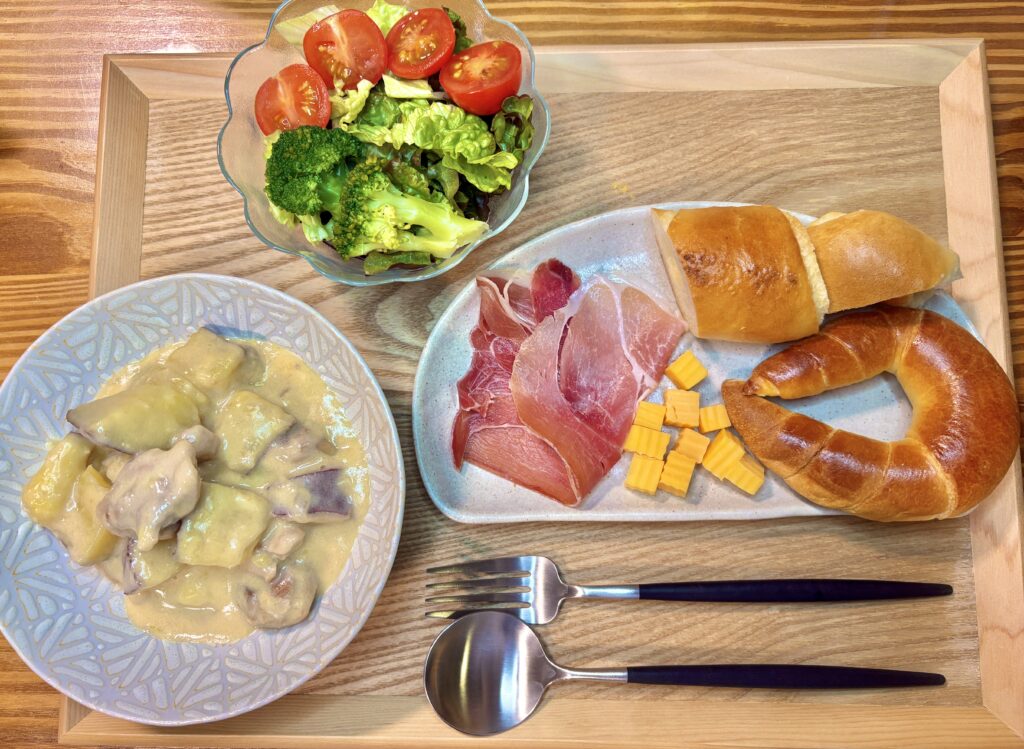 にんにく香るシュクメルリに、イスズベーカリーのパン、生ハムとチーズ、ブロッコリー入りサラダを添えたおうちバル風の食卓写真。