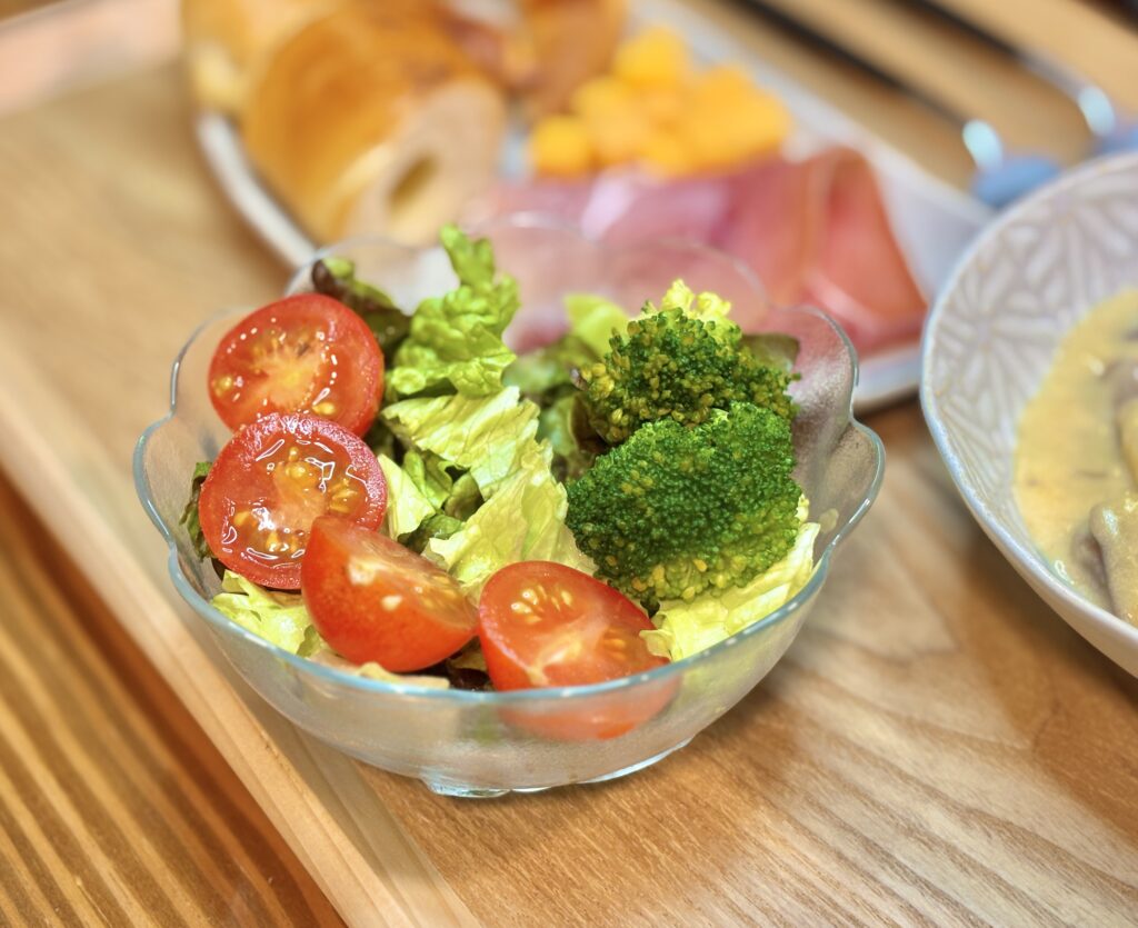 レタスとブロッコリー、ミニトマトを盛りつけたシンプルなサラダを、ガラスの器に入れた写真。