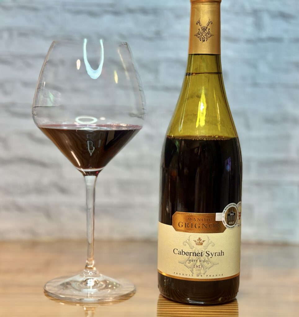 グラスに注いだ赤ワインと、カベルネ・シラーのボトルを並べて撮影した写真。