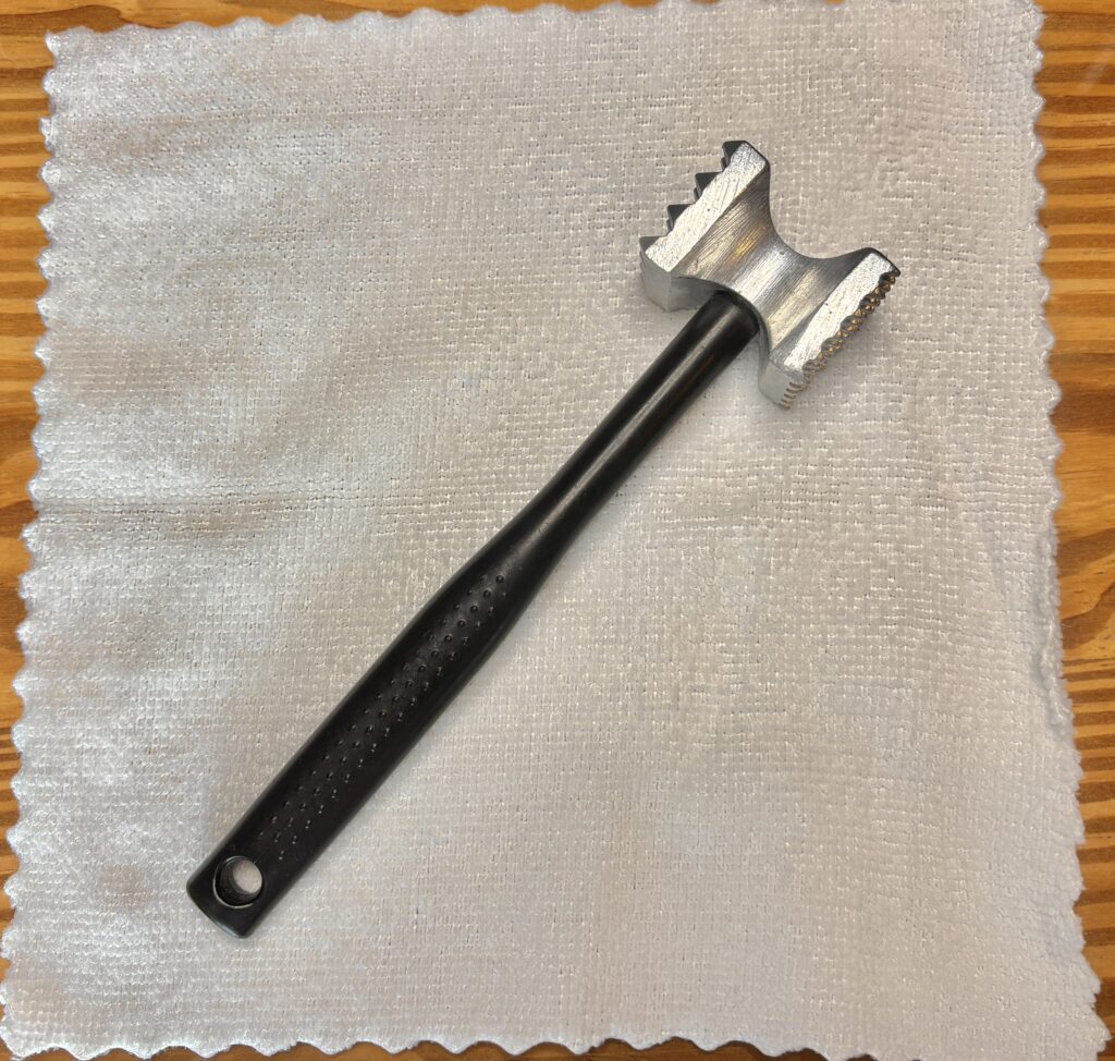 鶏肉の下処理に使うミートハンマーを白い布の上に置いた写真