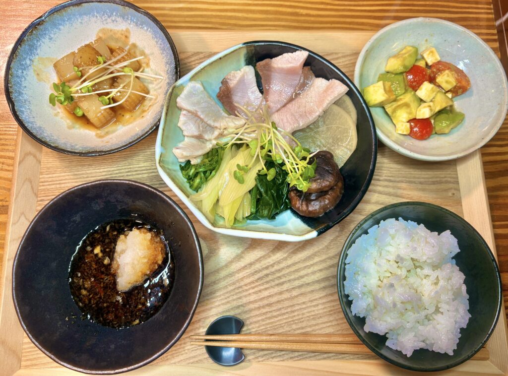 白身魚の湯引きと野菜を盛り合わせた主菜に、ごはん、アボカドとトマトの和え物、大根の煮物を並べた和定食の食卓