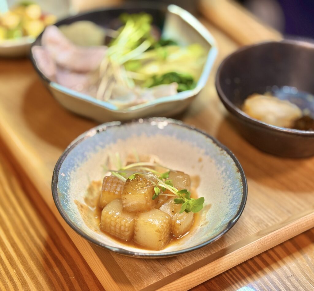 香ばしく焼いたこんにゃくステーキにかいわれを添えた小鉢料理。甘辛い味付けがしっかり染みて食欲をそそる一品