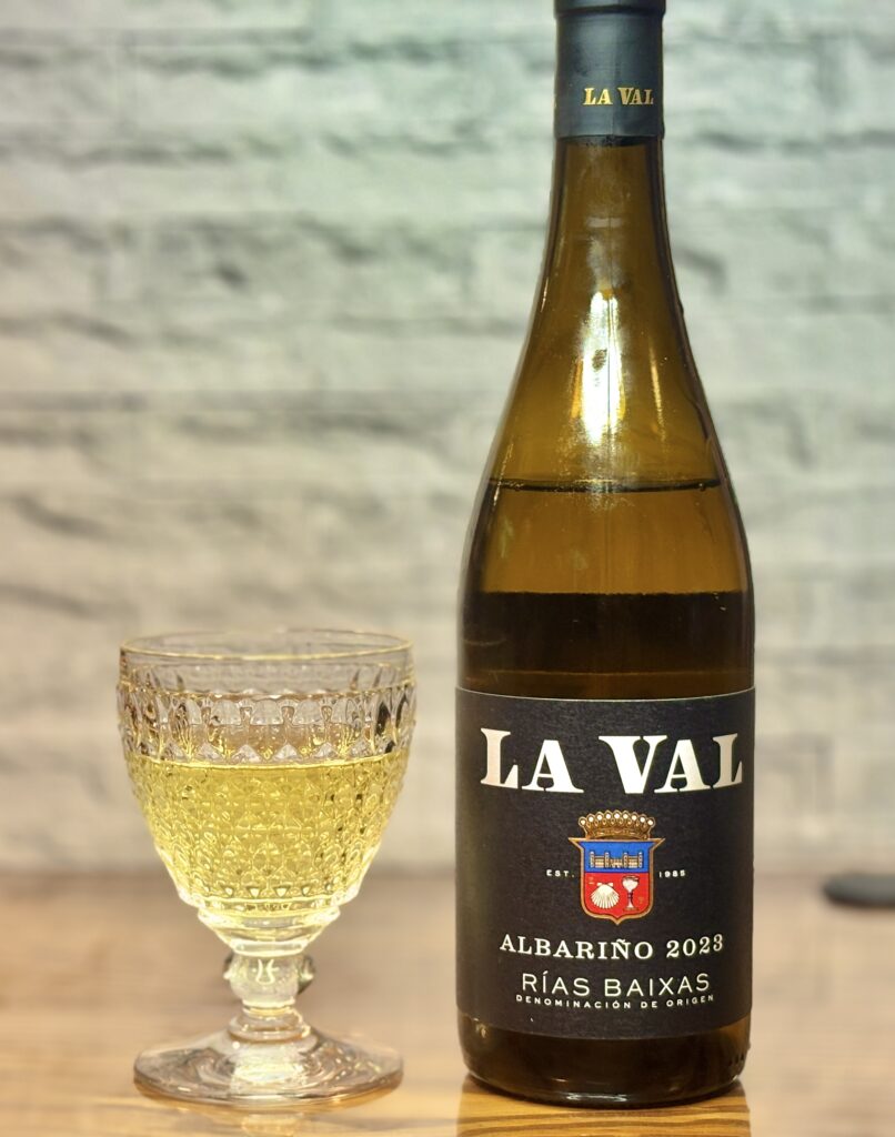スペイン・リアスバイシャス産の白ワイン、ラ・バル アルバリーニョ2023のボトルと、淡い黄金色のワインを注いだグラスを並べた写真。魚介料理に合う爽やかな白ワイン。