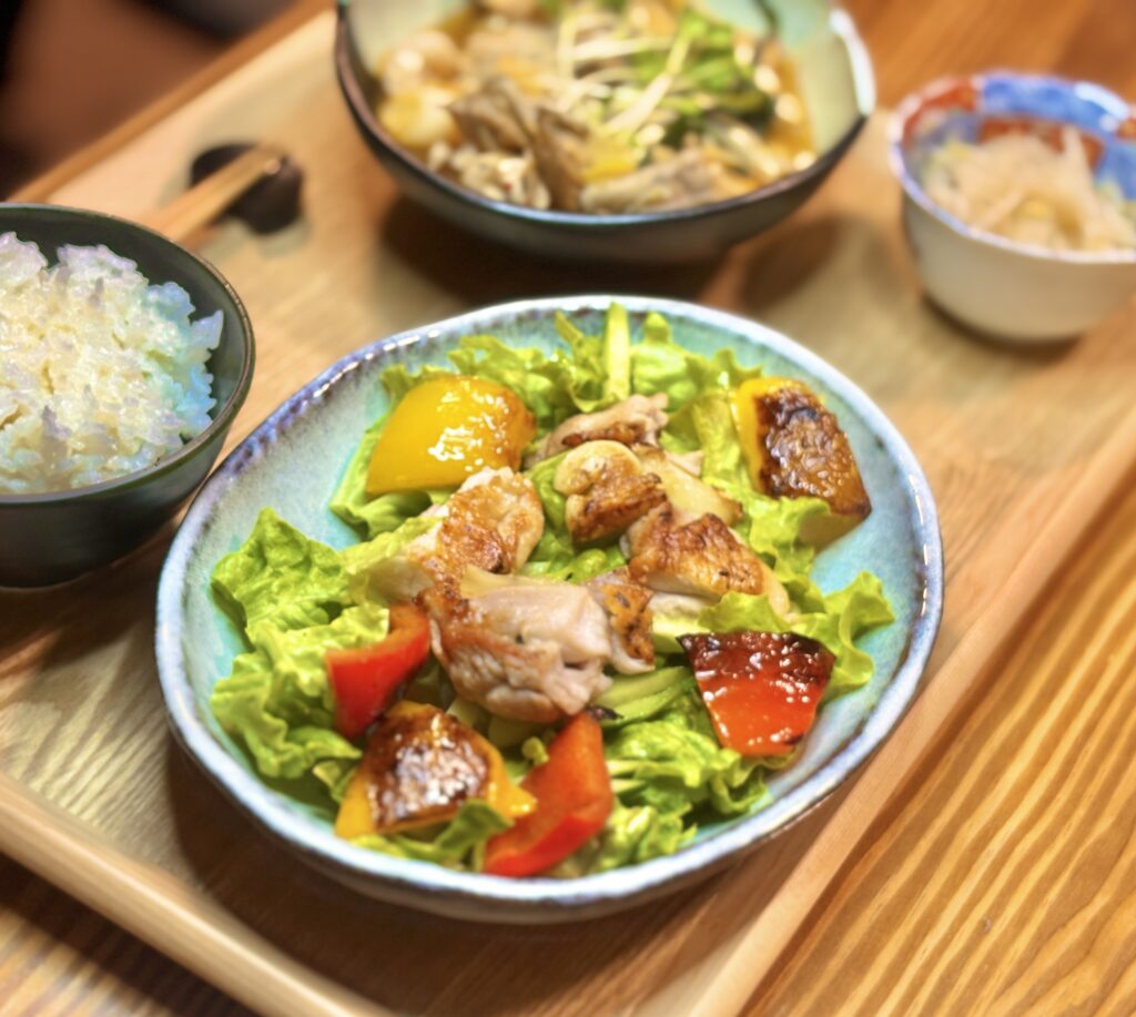 焼き目をつけたチキンと赤黄パプリカをのせたサラダのアップ写真