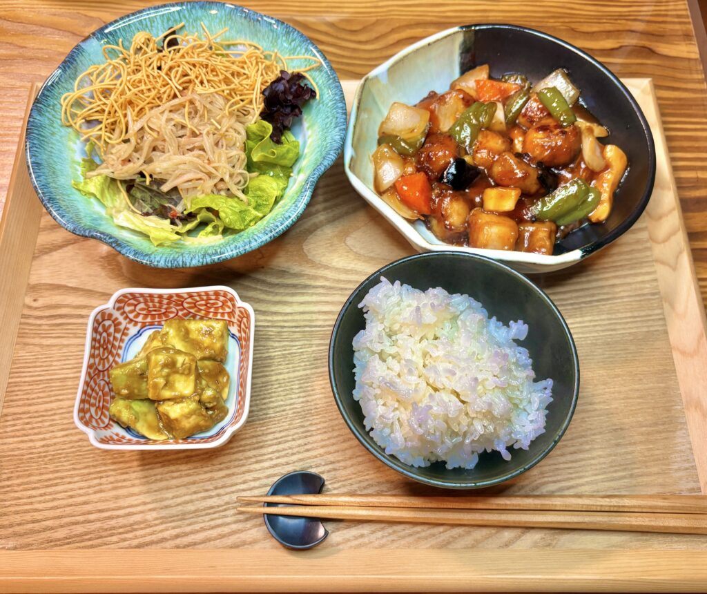 酢豚とカニカマもやしのラーメンサラダ、アボカドのワサビ和えが並んだ中華定食の献立写真