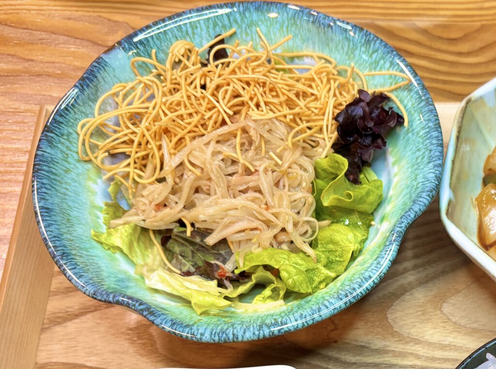 青い器にたっぷり盛られた、パリパリ麺とカニカマもやしのサラダのアップ写真