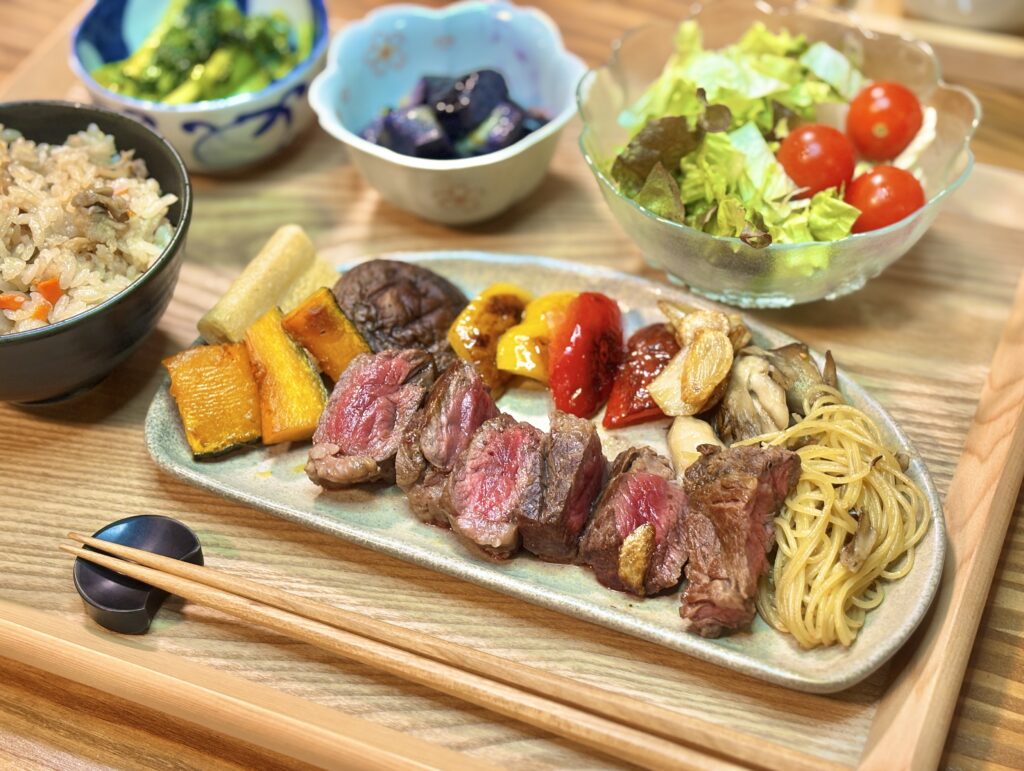 絶妙なレア加減に焼き上げられたアンガス牛ステーキの断面。付け合わせの焼き野菜(カボチャ・パプリカ)と舞茸の塩パスタが添えられた、食欲をそそる盛り付け。