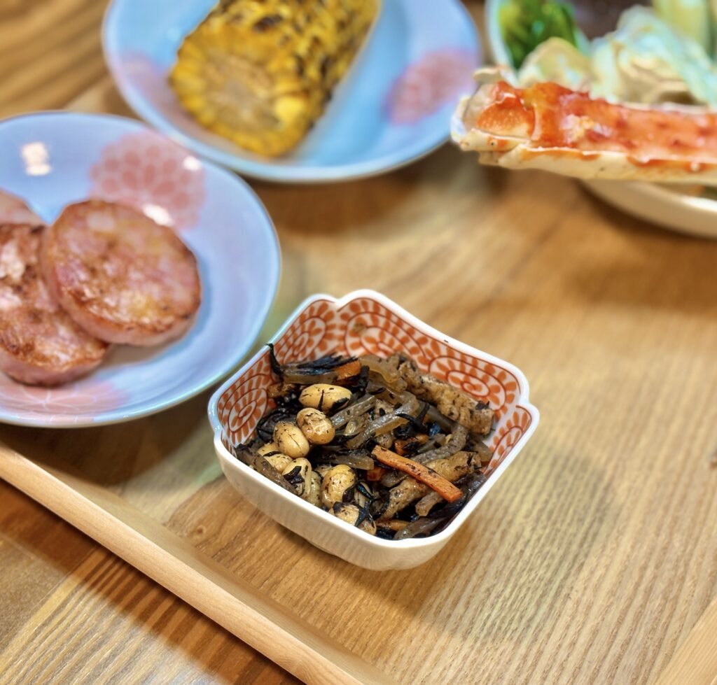 小鉢に盛り付けられた具だくさんのひじき煮。ふっくらした大豆、人参、油揚げが入った旦那キッチン手作りの副菜
