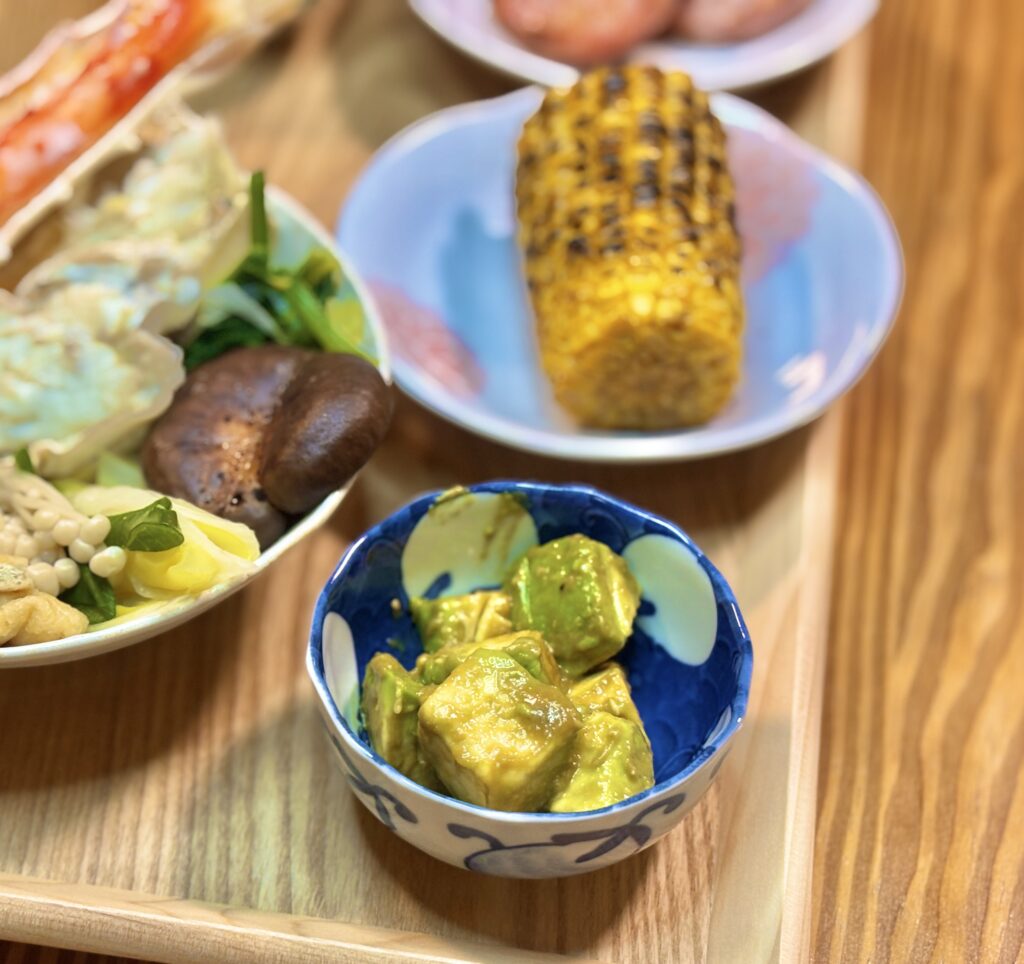 青い小鉢に盛り付けられたアボカドのワサビ醤油和え。ねっとりと濃厚でクリーミーな質感が伝わる、旦那キッチンのおつまみ一品
