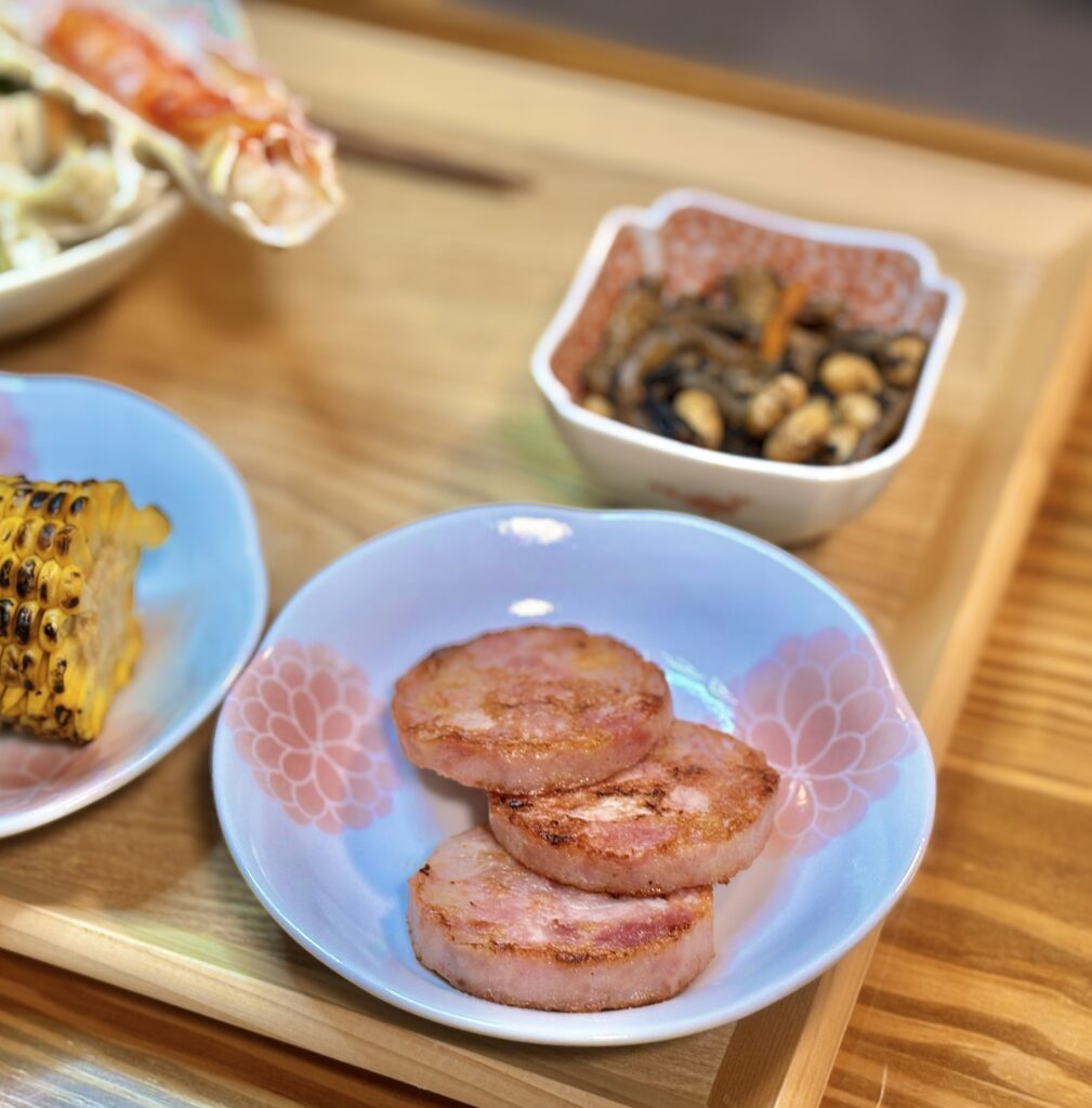 こんがりと焼き色のついた厚切り明方ハムのステーキ。お花の形の青いお皿に盛られた食欲をそそる一品
