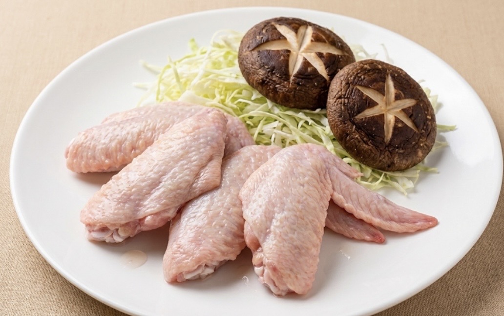 皿に並べた生の鶏手羽先と、星形の切り込みを入れたしいたけ、千切りキャベツの下準備食材