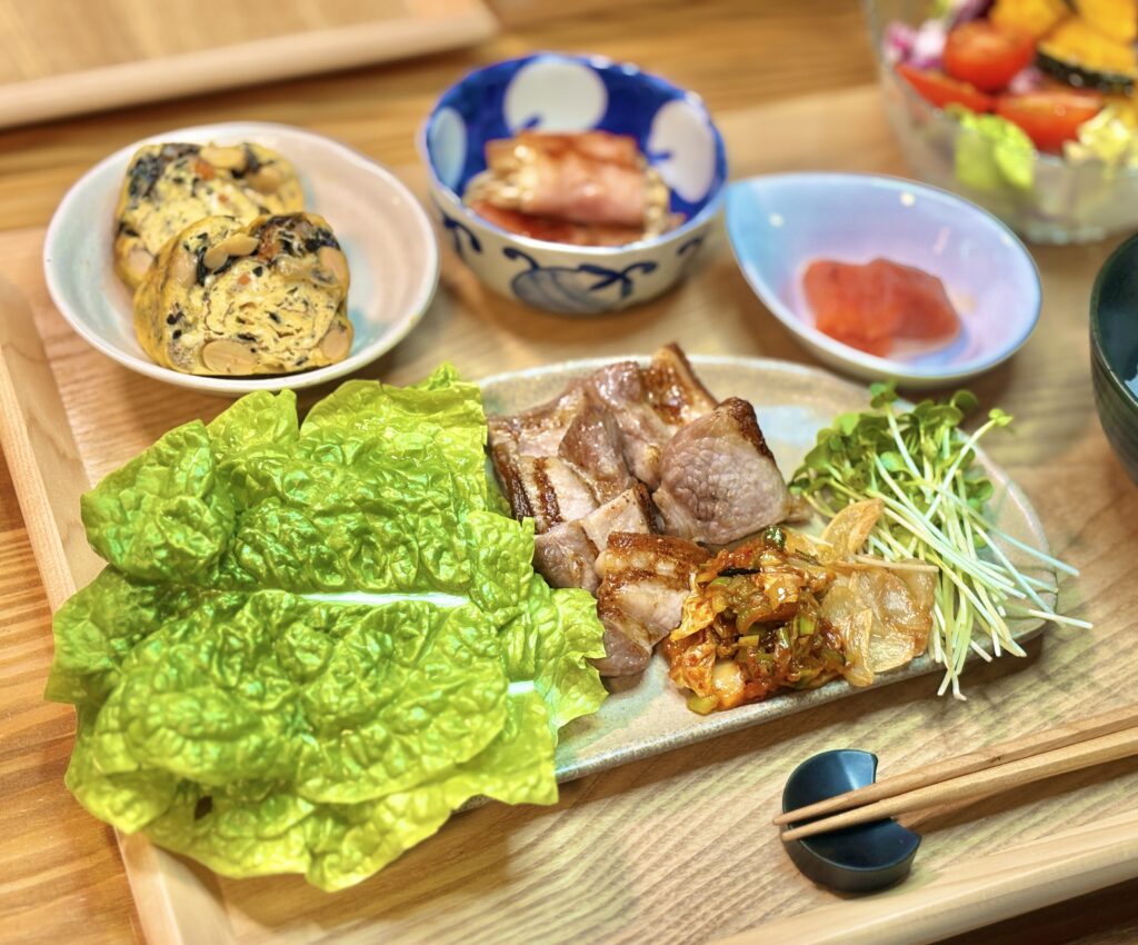 厚切りの豚バラ焼きをメインに、サンチュ、キムチ、フライドガーリック、かいわれ大根が添えられたプレートのアップ。