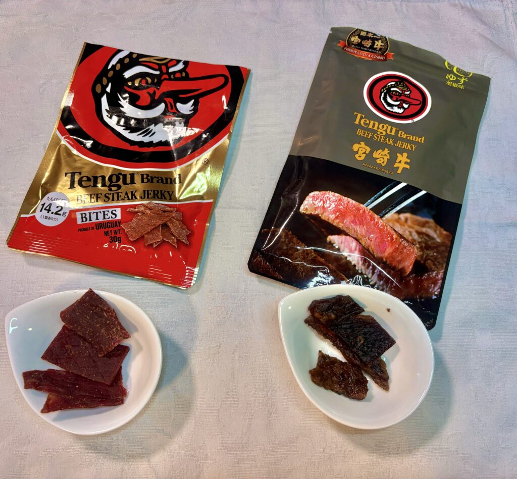 「テング ビーフジャーキー」のレギュラー(赤)と宮崎牛ゆず胡椒味(黒)のパッケージ。手前の小皿には、それぞれのジャーキーの中身が出されている。