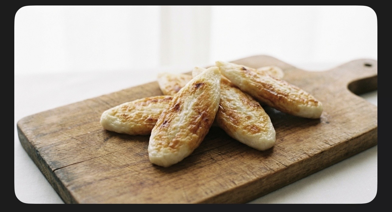 木のまな板の上に置かれた笹かまぼこ。白を基調とした明るくぼかした背景