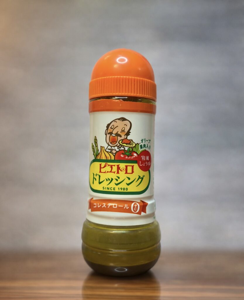 オレンジ色のキャップが特徴的な、ピエトロドレッシングのボトル。ラベルにはおなじみのコックさんのイラストが描かれ、「SINCE 1980」の文字と「和風しょうゆ」の赤いマークが見える。背景にはWordPressの投稿編集画面がうっすらと映り込み、ブログ執筆中のリアルな空気感とともに、家庭の食卓に欠かせない定番ドレッシングであることが伝わる一枚。
