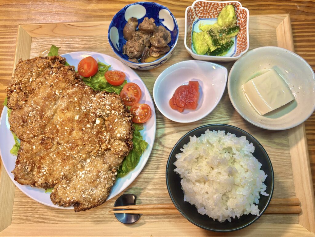 台湾唐揚げダージーパイをメインに、レバーの甘露煮、叩ききゅうり、明太子、ビールなどが所狭しと並んだ、豪華なおうち居酒屋の定食トレーの俯瞰写真
