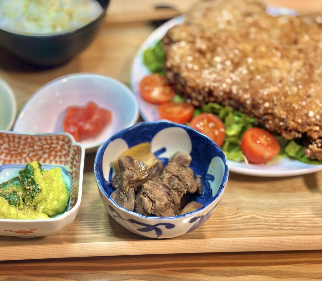 手前にある照りが美しい生姜入りの鶏レバーの甘露煮と、奥にある柄付きの器に盛られた叩ききゅうりの小鉢のアップ
