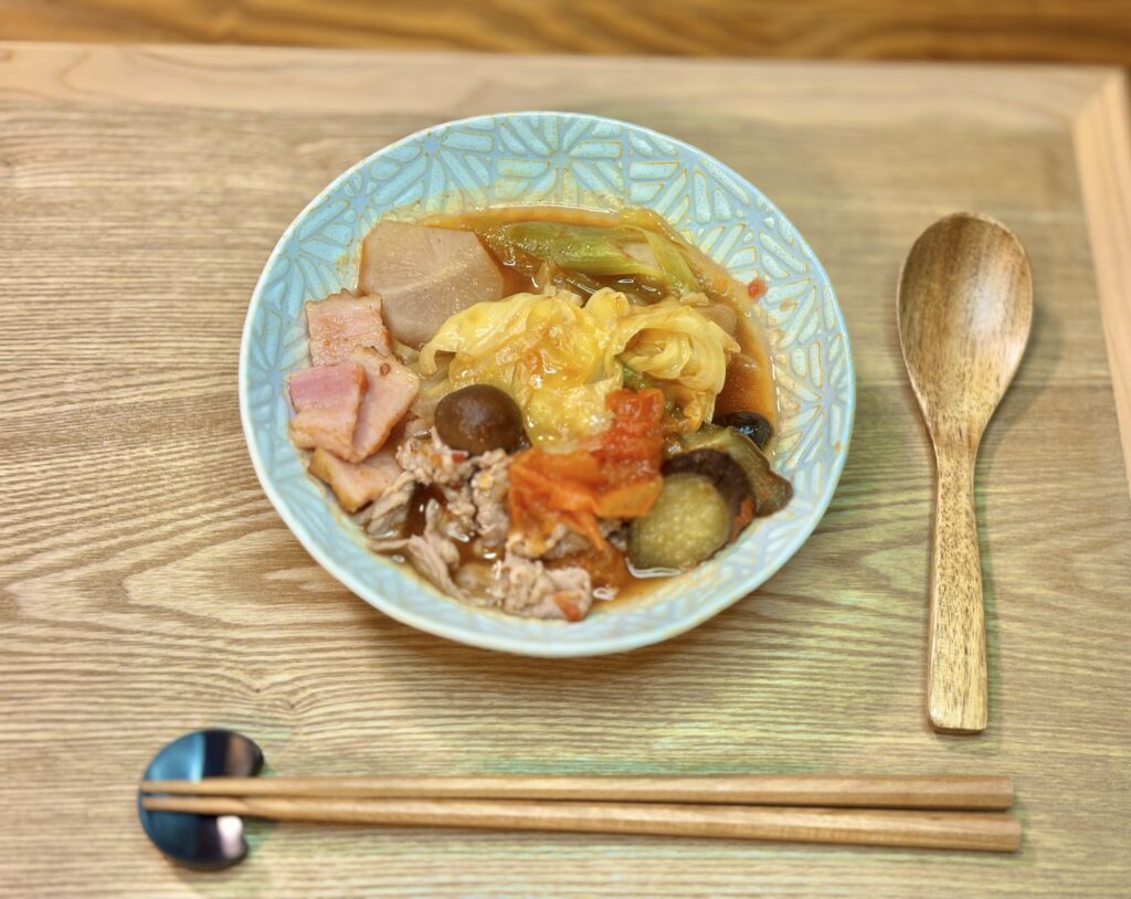 和風トマト鍋を器に盛り付けた一杯。トマトの赤と野菜の色合いが映え、出汁の効いたスープが食欲をそそる。