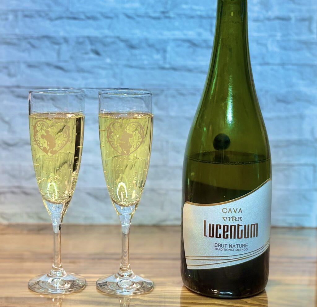 スパークリングワインとグラスの写真。CAVAのボトルと、淡い黄金色の泡が立つシャンパングラスが並んでいる。