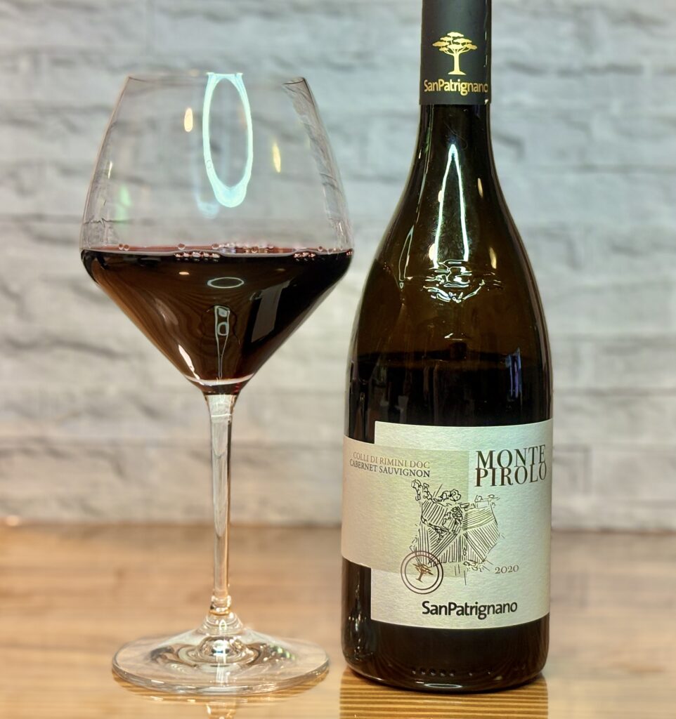 ワイングラスに注がれた赤ワインとボトルの写真。ボトルラベルにはMONTE PIROLO 2020、San Patrignanoの表記がある。