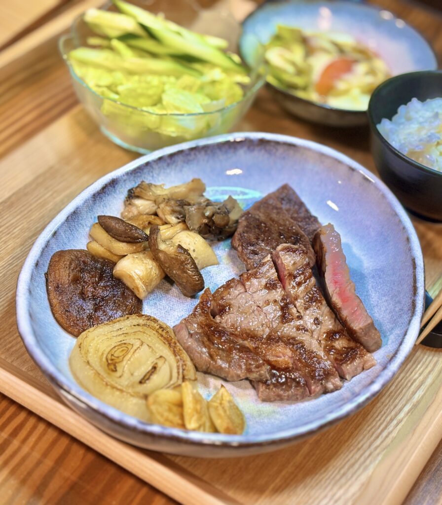ミディアムレアに焼いた黒毛和牛ステーキとエリンギ・舞茸・椎茸のガーリックソテー、焼き玉ねぎを盛り合わせた一皿
