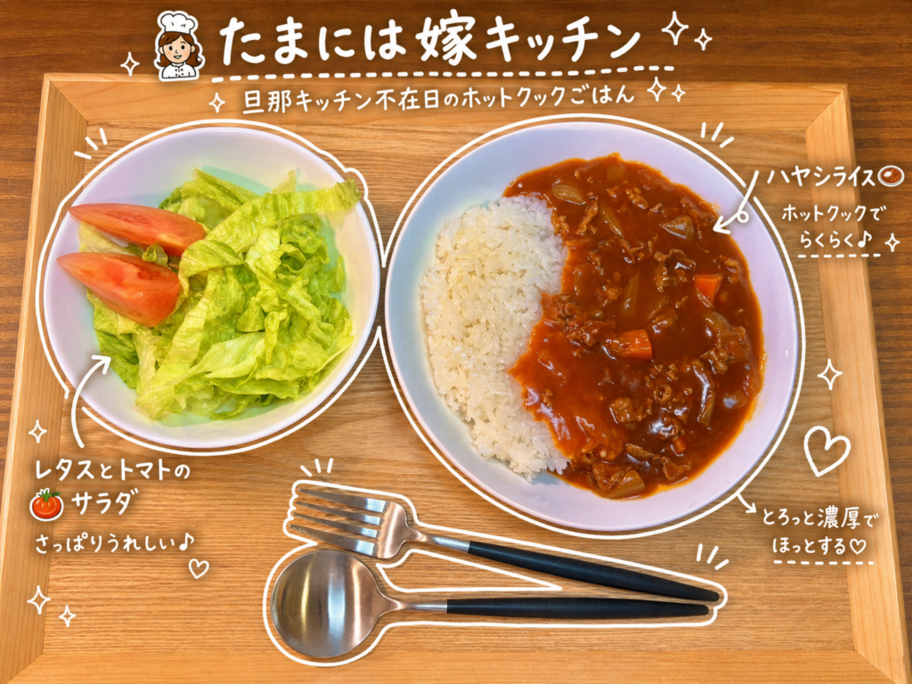 木製トレーの上に、白い器に盛られたハヤシライス。右半分にとろみのあるルーがかかり、牛肉や玉ねぎ、にんじんが見える。左側にはレタスとトマトのシンプルなサラダの小鉢。手前には黒い持ち手のスプーンとフォークが並べられている。