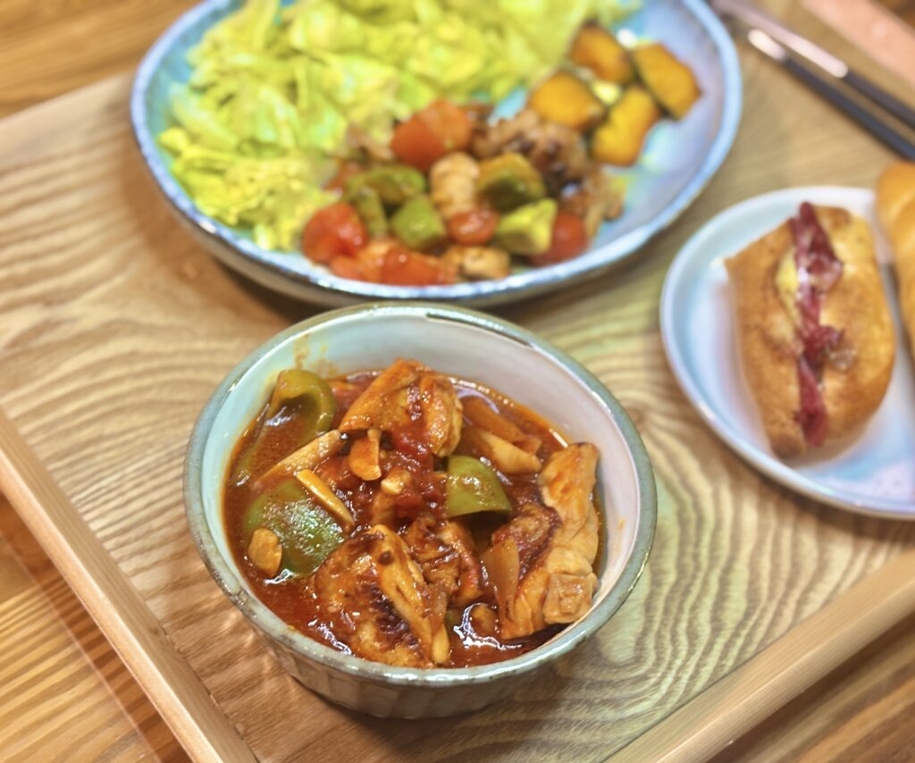 器に盛ったグリーンパプリカと鶏肉のトマト煮込み。赤いソースの中に鶏肉と野菜がごろっと入り、温かい煮込み感が伝わる近景。