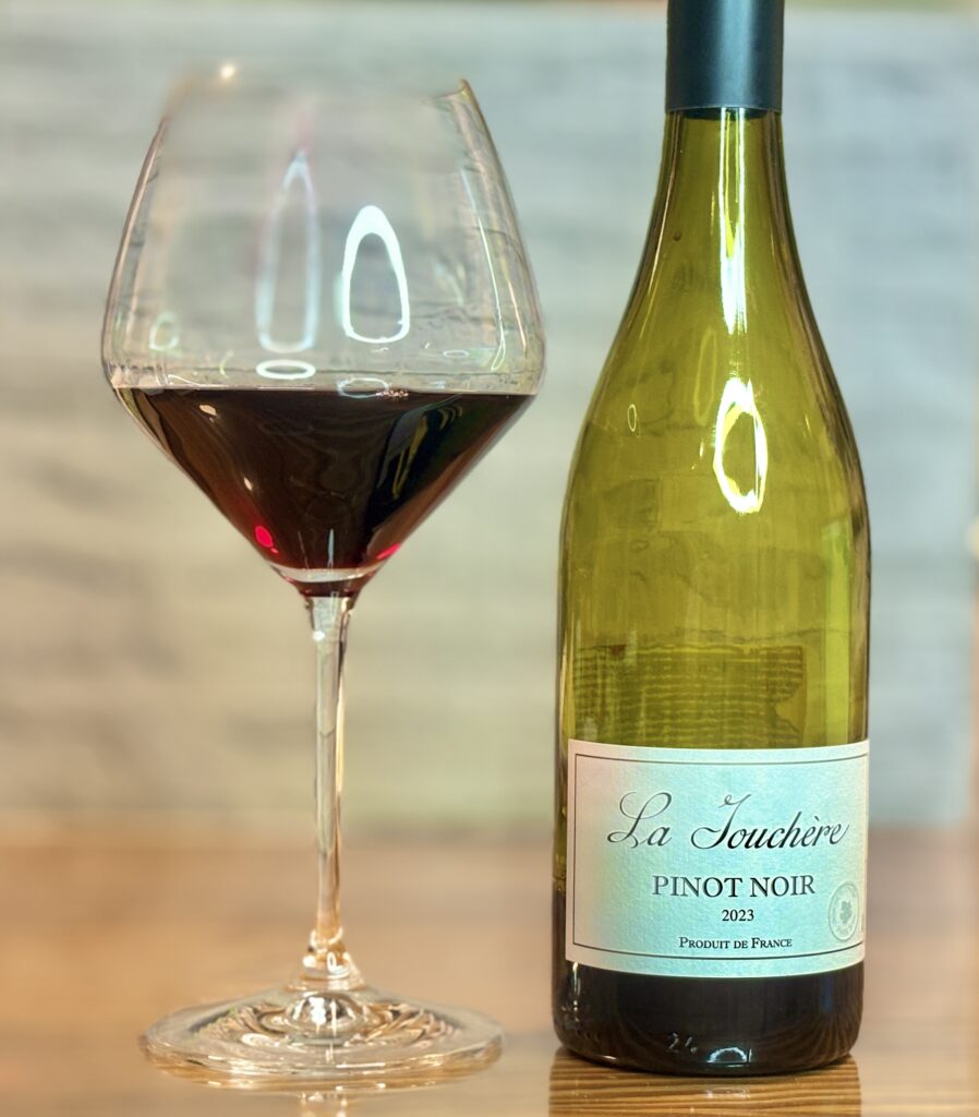 フランス産赤ワイン「La Touchere Pinot Noir」とワイングラスに注いだ赤ワイン。食事と合わせて楽しむ家庭の晩酌シーン。
