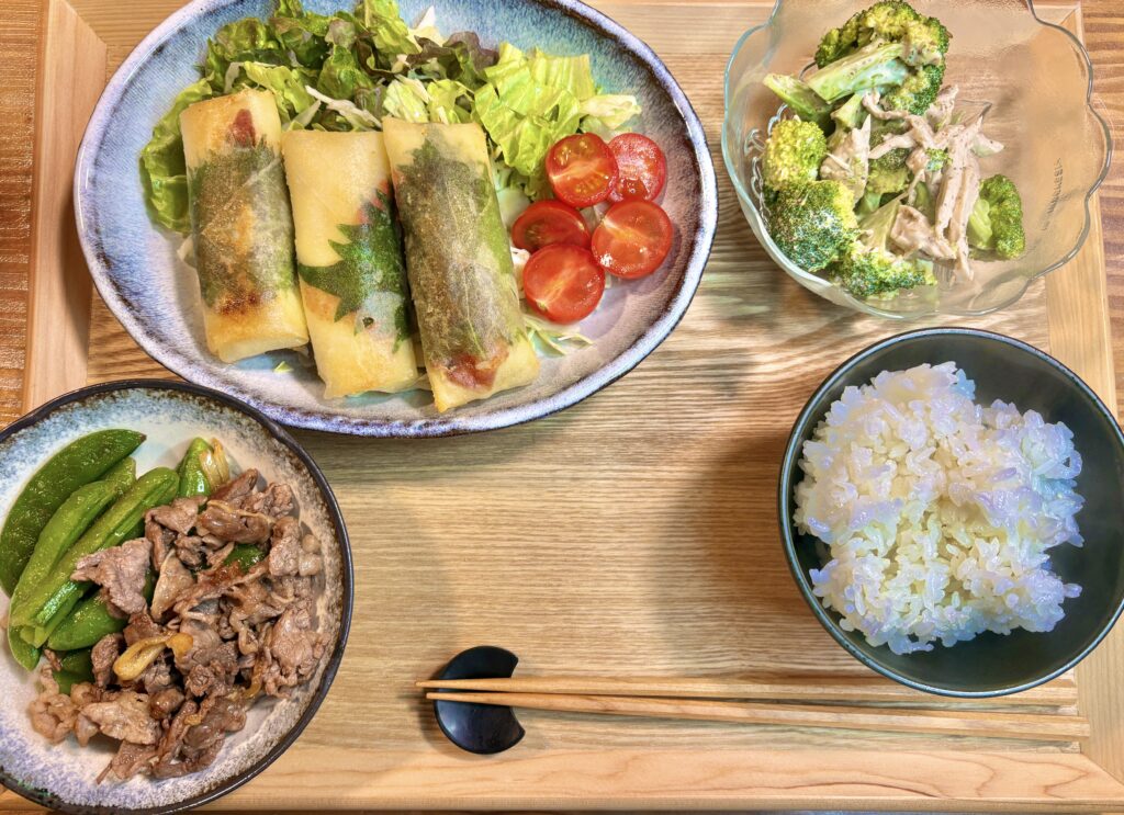 鶏むね肉とチーズと紫蘇の春巻き、牛肉とスナックえんどうのガーリック炒め、鶏むね肉とブロッコリーの胡麻ドレッシング和え、ご飯を並べた晩ごはんの和食プレート