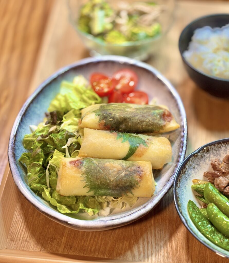 紫蘇の葉が透けて見える鶏むね肉とチーズの春巻きをレタスとミニトマトのサラダと一緒に盛り付けたメインプレート
