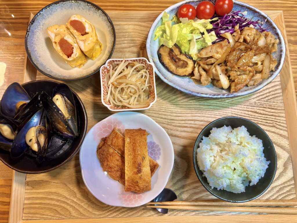 タモリ流豚の生姜焼き、ムール貝のワイン蒸し、明太子入り卵焼き、もやしのガーリック炒め、イカ天ぷら、ごはんを並べた「旦那キッチン」の家飲み晩ごはんの食卓全体写真。