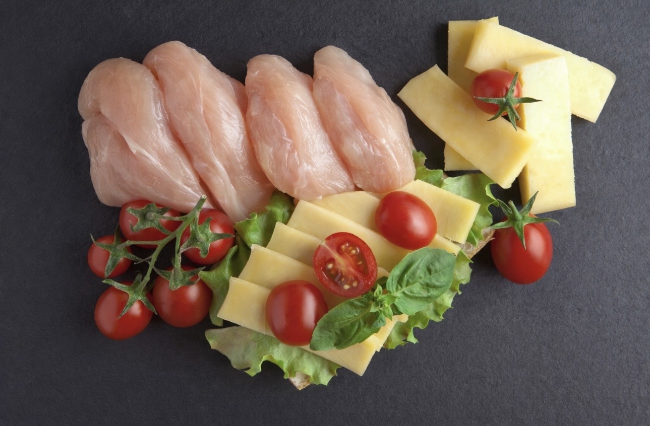 鶏ささみ肉、スライスチーズ、ミニトマト、レタスを黒い背景に並べた食材写真。高たんぱく低脂質の鶏ささみとチーズ、野菜を組み合わせた料理素材のイメージ。