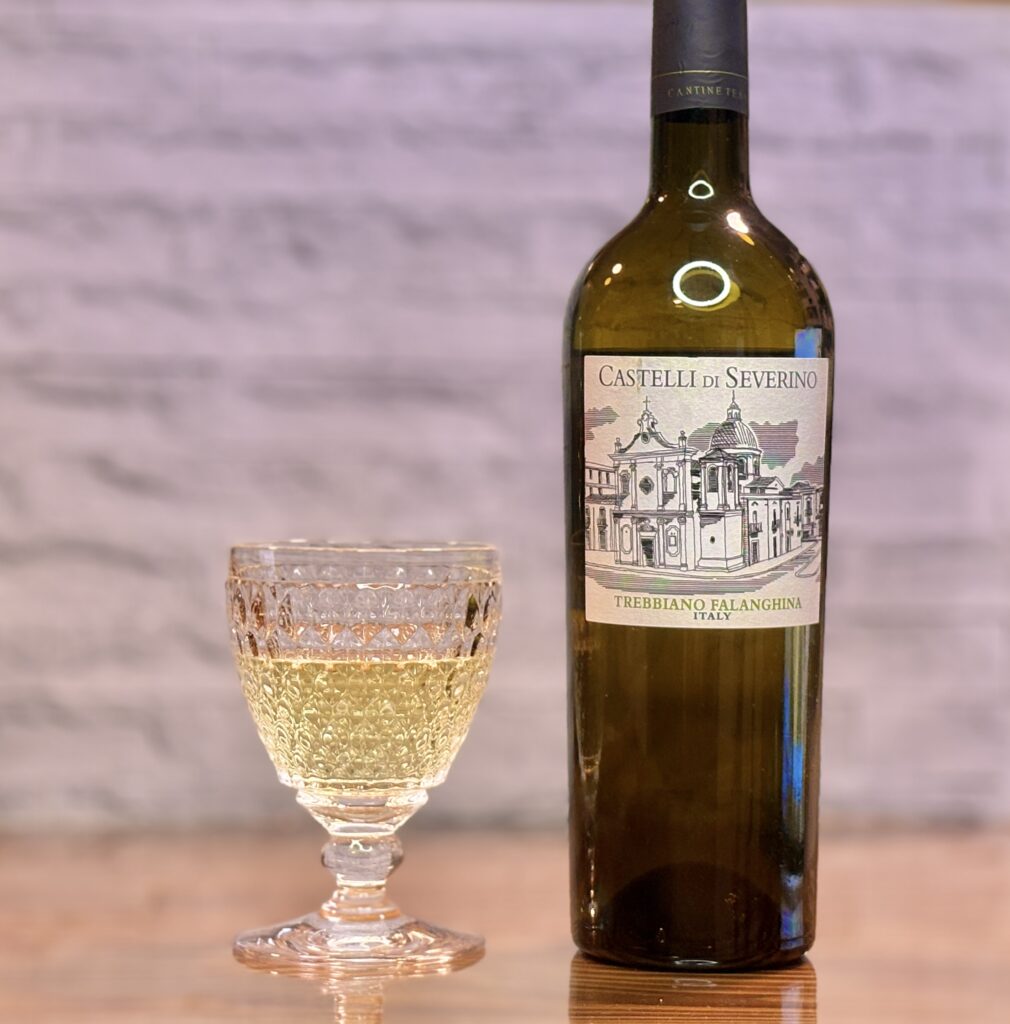 イタリア白ワイン「カステッリ・ディ・セヴェリーノ トレッビアーノ・ファランギーナ」のボトルとグラス。淡い黄金色のワインが注がれたグラスとともに、家飲みディナーを彩る落ち着いた雰囲気のワイン写真。