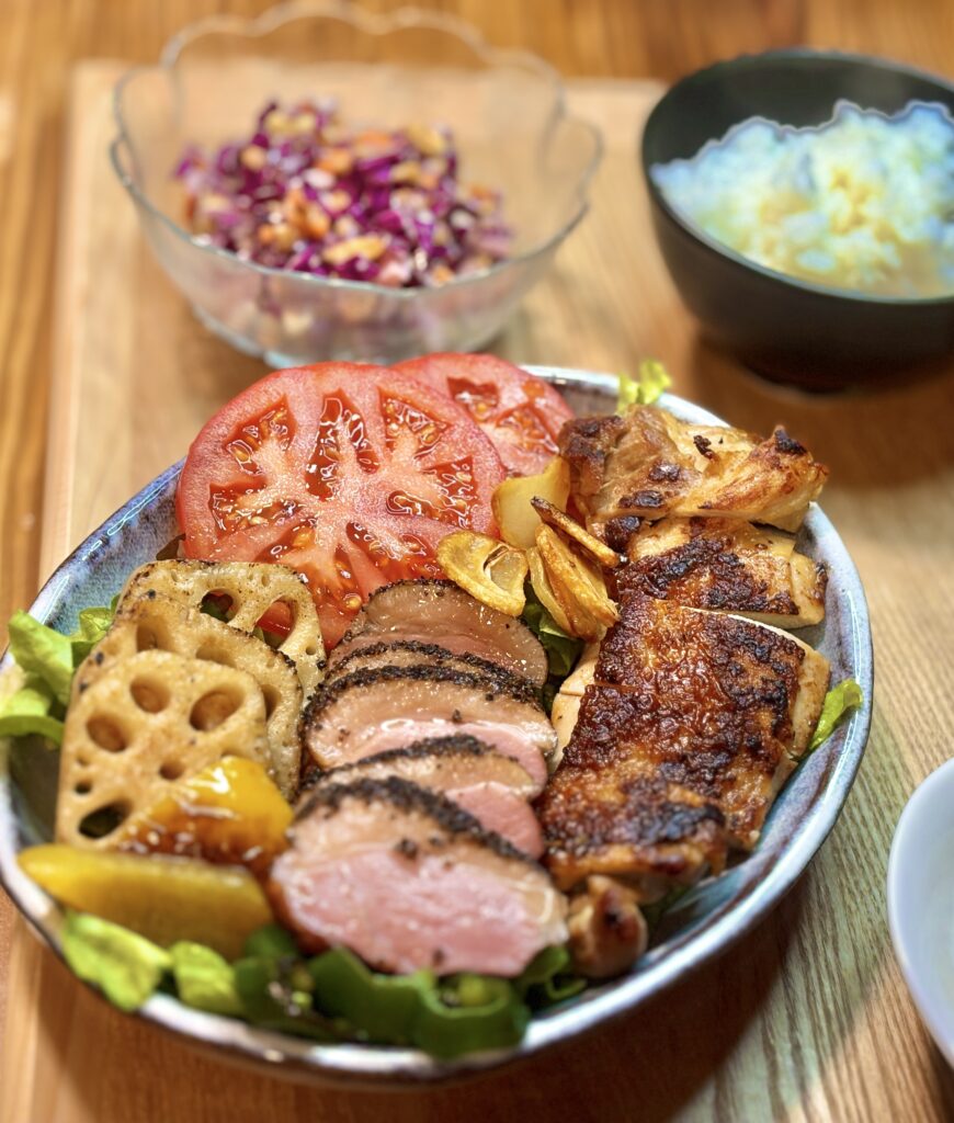 こんがり焼いたチキンソテーとブラックペッパー香るパストラミ鴨を盛り付けたワンプレート。レンコンとパプリカのガーリックソテー、トマト、葉野菜を添えた彩り豊かなメインプレート。