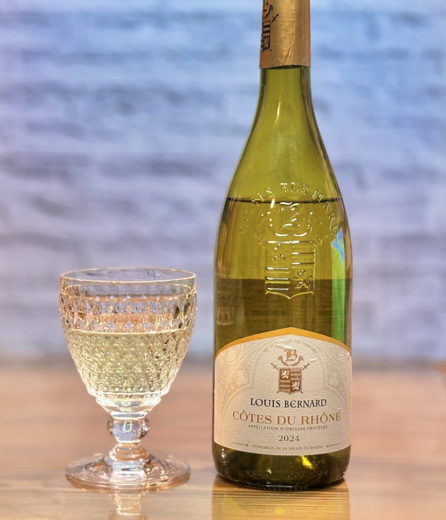 ルイ・ベルナール コート・デュ・ローヌ ブラン 2024のボトルと、白ワインを注いだグラスを並べた写真。淡いゴールド色の白ワインがきれいに映え、今夜の魚料理やバゲットに合わせた食卓ワインとして上品な雰囲気を演出している。