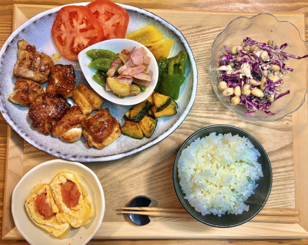 ハニーマスタードチキンが主役の晩ごはんプレート。鶏もも肉のハニーマスタードチキン、スナックえんどうとベーコンのガーリック炒め、焼き野菜(かぼちゃ・パプリカ・ピーマン)、トマト、明太子卵焼き、紫キャベツと鶏胸肉と豆の胡麻ドレサラダ、ご飯が並ぶ旦那キッチンの家庭料理。