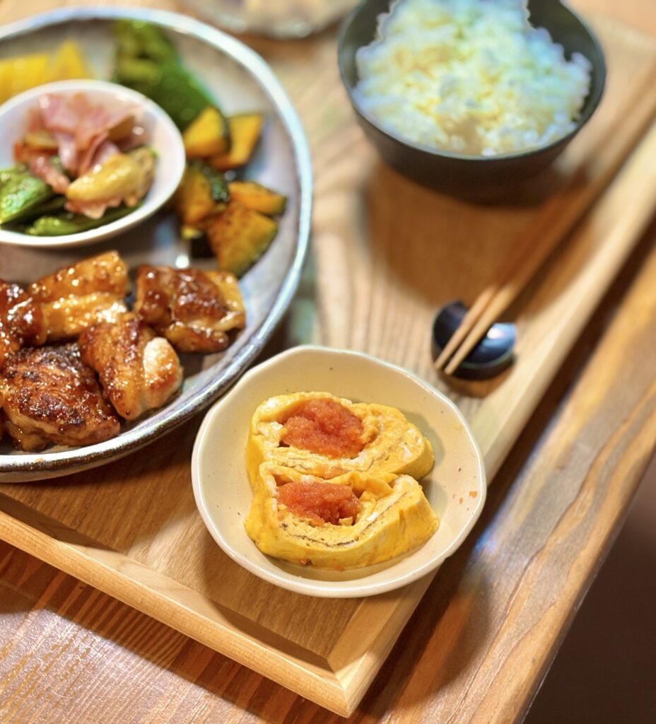明太子入り卵焼きとハニーマスタードチキンの家庭ごはん。ご飯と副菜が並ぶ木製トレイの和風ワンプレート晩ごはんのクローズアップ写真。