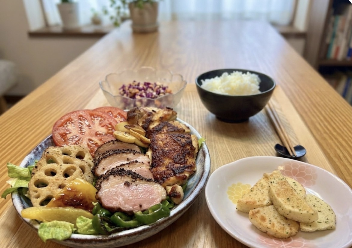 チキンソテーとパストラミ鴨を盛り合わせたワンプレートごはん。レンコンとパプリカのガーリックソテー、トマト、サラダを添え、別皿に青のり長芋フライ、奥に紫キャベツとにんじんのコールスローと白ごはんを並べた家庭の晩ごはん。