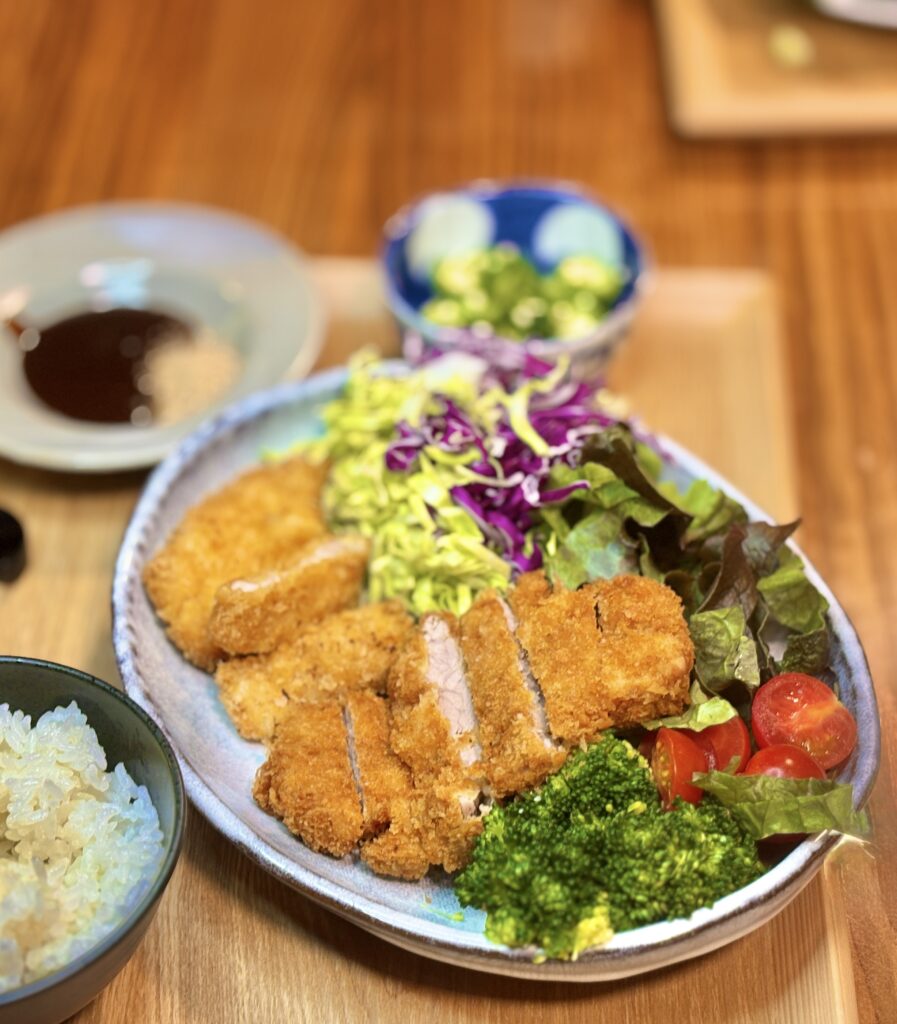 サクサク衣のロースカツとヒレカツを盛り付けたお皿のアップ。やわらかい断面と新鮮野菜が美味しそうなとんかつプレート
