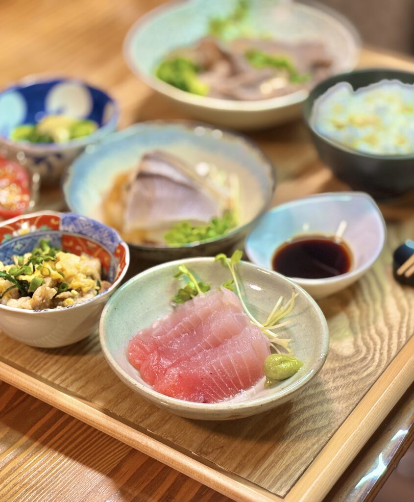 桜ビンチョウマグロのお造りを中心にした和食プレート。小鉢料理やご飯とともに並ぶ家庭の贅沢ごはん。
