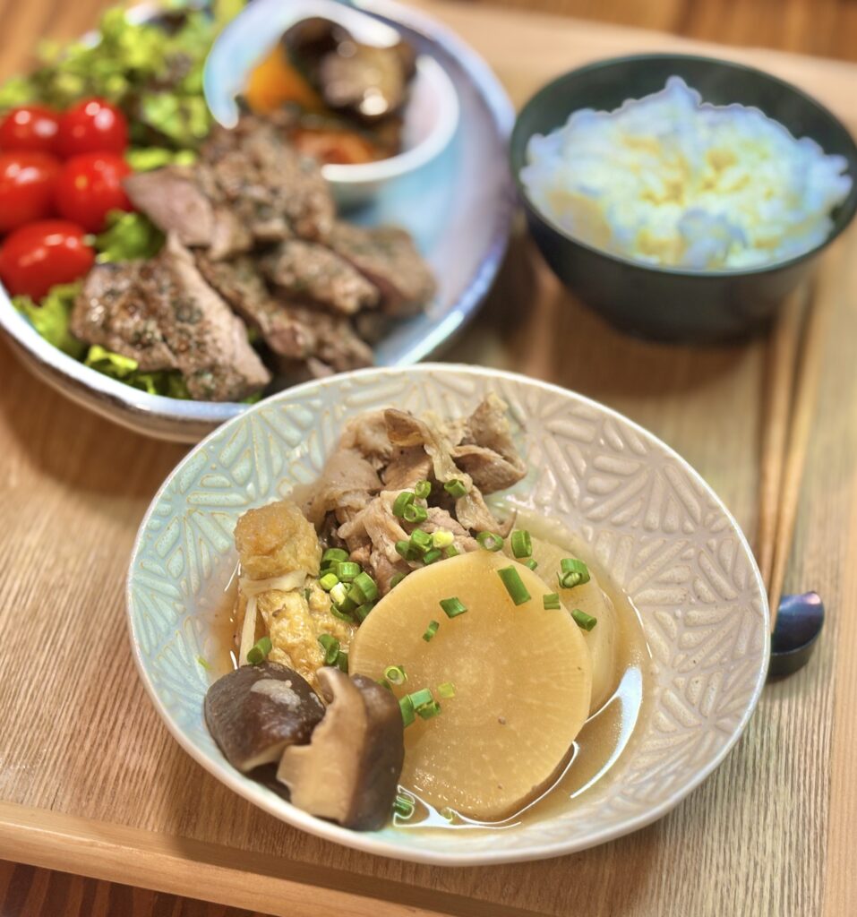 豚こまと大根と椎茸の煮物のアップ写真。味がしみた大根と豚肉、椎茸に青ねぎを散らした家庭料理