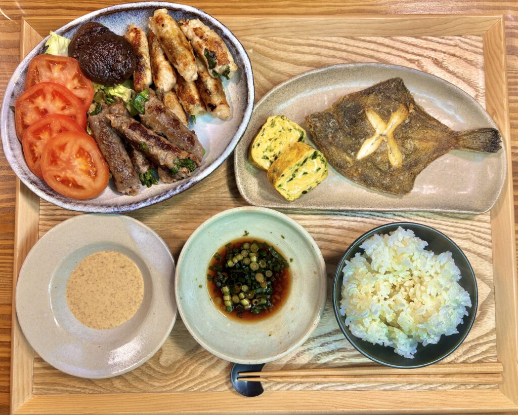 メダカカレイの唐揚げと青さのりの卵焼き、豚肉と牛肉の野菜巻き、トマトスライス、焼き椎茸を盛り付けた和風献立。ごまだれとポン酢を添えたバランスの良い家飲みごはん。