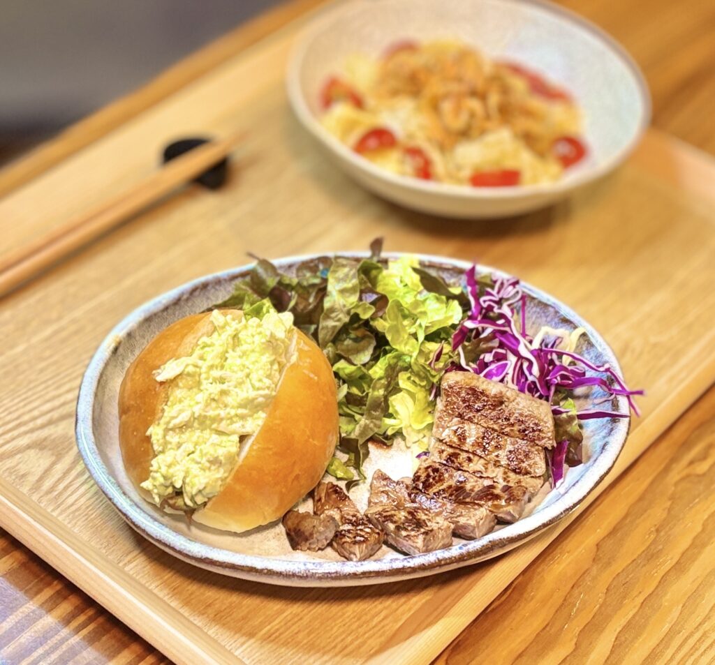 アボカドとクリームチーズと鶏胸肉をマヨネーズとごまドレッシングで和えたサンドと、焼き目のついた牛モモ肉のソテー、グリーンリーフや紫キャベツのサラダを盛り付けたワンプレート。