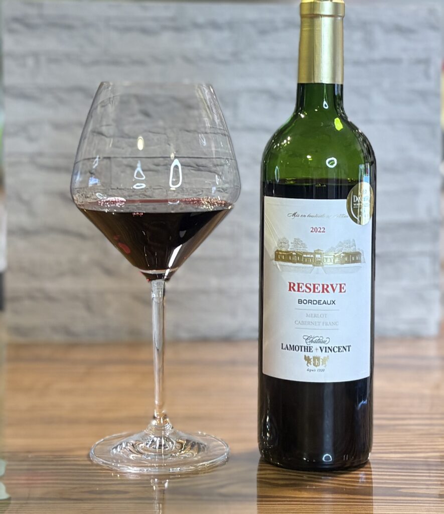 赤ワインを注いだワイングラスとボルドーワインのボトル。ビーフシチューに合わせた上品なテーブル演出。
