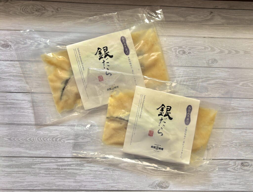 西京味噌にじっくり漬け込まれた銀鱈の切り身を真空パックで保存した状態の写真。脂ののった銀鱈と甘みのある味噌が特徴で、焼くだけ簡単に本格和食が完成する人気のお取り寄せグルメ・魚料理。